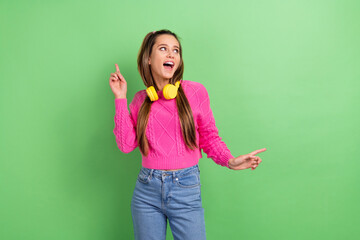 Portrait of good mood girl with stylish hairdo wear knit pullover in headphones dance look empty space isolated on green color background