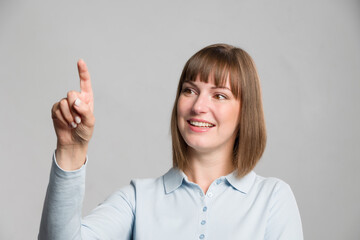 Portrait of a young brunette woman in a polo shirt is pointing