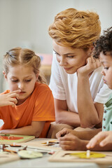 Obraz na płótnie Canvas kid talking to teacher near child and didactic material in montessori school
