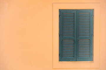 Yellow stucco wall with green shutters.  Taken in Italy.  Symmetry with shutters on right hand site as an example of the rule of thirds. 