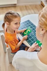 clever girl and teacher holding numbers near chalkboard, learning through play, math, top view