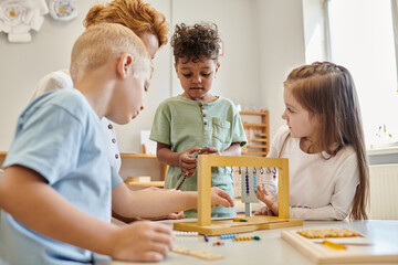 cute kids looking at african american boy playing educational game in montessori school, diversity