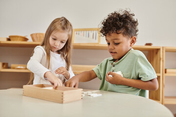 Fototapeta premium math learning, african american boy playing with girl, montessori school concept, diverse kids