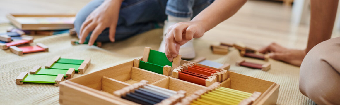 montessori school concept, cropped view of girl playing color matching game near teacher, banner