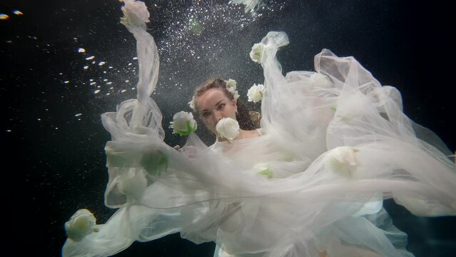tender bride in wedding dress swimming alone in pool, underwater shot, pretty lady diving in depth