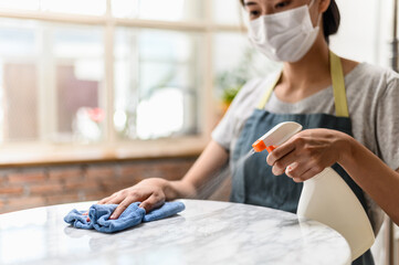 Close up hand of woman cleaning marble stone table using clothes and cleaning solution.