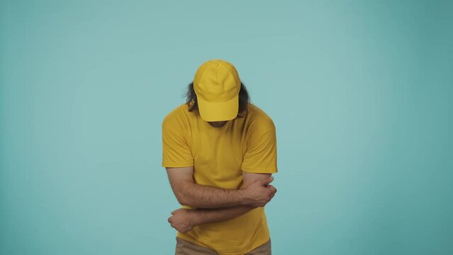 Delivery man in yellow uniform tries to cath a box with fragile stickers placed all over the package but misses it. Isolated on blue background.
