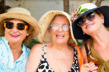 Outdoor portrait of three females old aged mature friends together having fun and smiling at the...