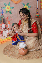 Janmashtami Concept. Mother sitting with her cute baby boy dressed up as little krishna.