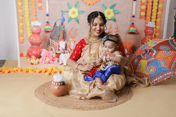 Janmashtami Concept. Mother sitting with her cute baby boy dressed up as little krishna.
