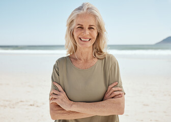 Fototapeta na wymiar Beach portrait, arms crossed and senior woman relax for outdoor wellness, nature freedom or travel holiday in Canada. Sand, ocean sea water and elderly person smile for retirement vacation happiness