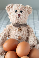 Teddy bear with brown eggs in a basket on the bed. - 639269700
