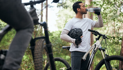 Forest, bike and man drinking water, exercise and fitness with workout, refreshing and wellness. Healthy person, athlete or cyclists in the woods, hydration and outdoor with liquid, nature and helmet