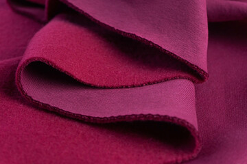 layers of French terry pink amaranth textile. A piece of fabric lies in beautiful waves. 