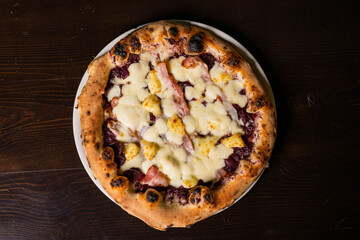 Pizza napoletana gourmet con mozzarella, pancetta e cavolo rosso fotografata dall'alto su un tavolo...