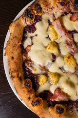 Pizza napoletana gourmet con mozzarella, pancetta e cavolo rosso fotografata dall'alto su un tavolo di legno