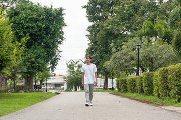 A young man wearing a white T-shirt takes a relaxing walk in the park. urban relaxation concept