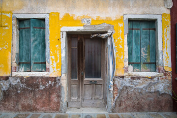 Il muro rovinato della facciata di una casa disabitata dipinta di giallo a Burano, isola della laguna di Venezia