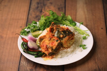 indian fish curry served with rice in a bowl closeup with selective focus and blur