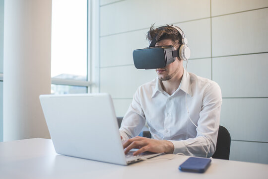 Young caucasian businessman using 3D viewer and pc