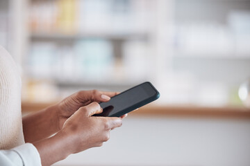 Woman pharmacist with smartphone, typing in clinic and research for medical information, email or online chat. Phone, networking and mockup, doctor in pharmacy checking social media or internet news
