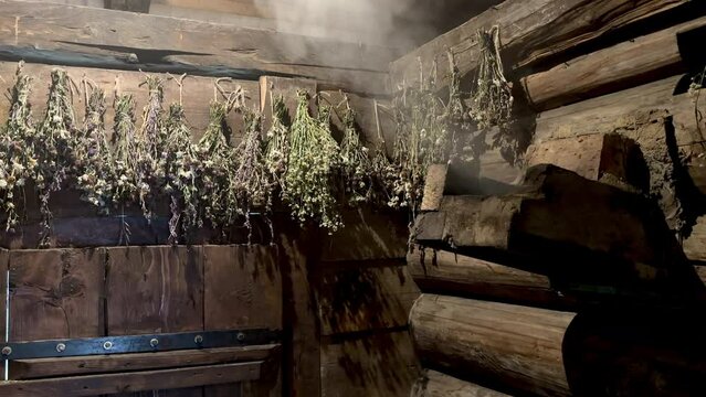 Wooden rural sauna with herbals. Wood heating smoke. Steam.