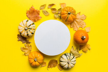 Autumn composition with round paper blank and dried leaves with pumpkin on table. Flat lay, top view, copy space