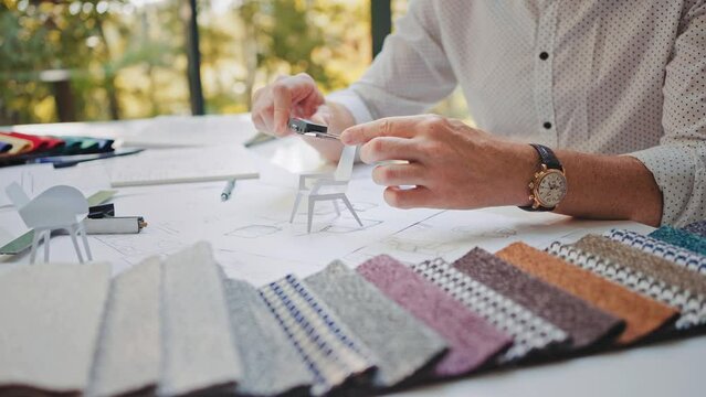 Man using caliper for chair scale model on desk with tools