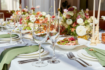 Aesthetic table setting with candles and flowers decorations. Restaurant chamber event under sunlight shadows.