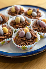 Chocolate pastries shaped like baskets with eggs, packaged in paper, rest on a plate