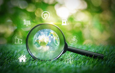 Magnifying glass focused on earth globe and smart icon on the grass in garden for choosing safe...