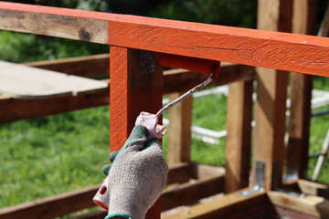 Worker applies a coat of wood preserver to protect wood from penetrating humidity. Home renovation concept. 