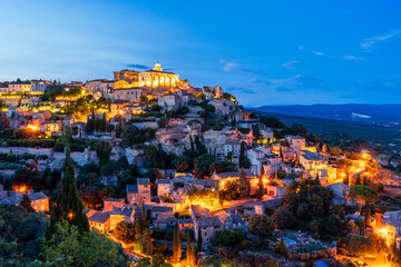 Night view of ancient Provencal town Gordes at dusk with warm lights on the streets. Gordes in...