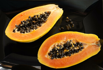 Papaya sliced in half on a black plate