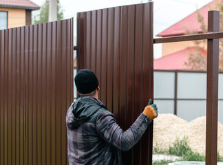 Workers install a metal profile fence