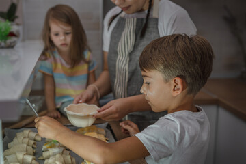 One woman with one toddler girl and one  preschooler boy in the kitchen making croissant and preparing for baking