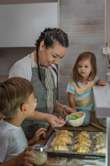 One woman with one toddler girl and one  preschooler boy in the kitchen making croissant and preparing for baking