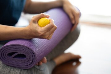 Hands of a woman squeezing a stress ball on the yoga mat, work out concpet