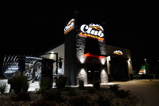 The club car wash building glows neon red and white during the night.