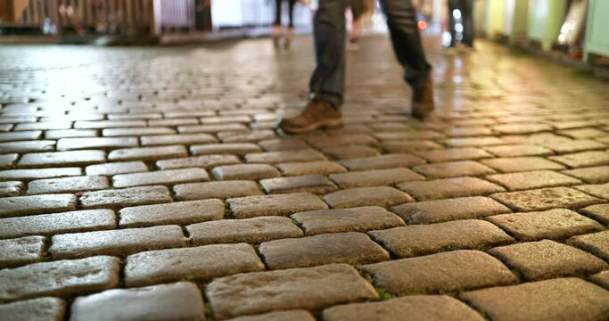 People walk along the cobblestone sidewalk stone brick sidewalk at night on the streets of Prague Czech Republic Czechia
