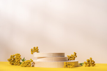 Wooden cylindrical podiums stack with yellow flowers on beige and yellow background. Podium,...
