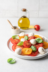 Appetizing Italian caprese salad. Tomatoes mozzarella basil salad close-up view on white background