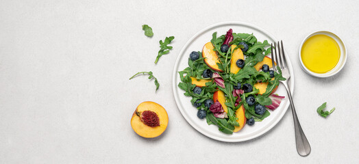 Peach arugula blueberry salad in plate on white background. Delicious fruit salad