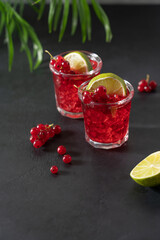 Red currant mojito in glasses with ice. Refreshing berry drink on black background