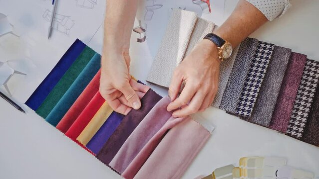 Male hands examining color swatches of fabrics for furniture