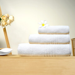 a stack of folded towels on a wooden shelf with a ladder in the background towels on wooden in bath