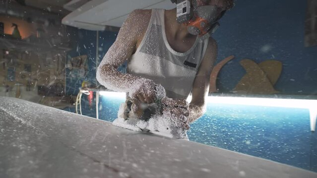 Male surfboard shaper making surfboard in his workshop. Hand shaping from blank.