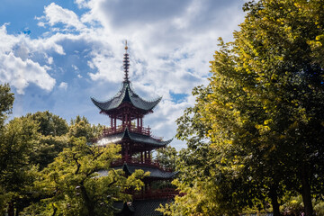 Fototapeta premium A slender tower of traditional Chinese architecture among trees in a forest.