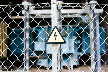 Danger sign, high voltage, on the fence of an electrical transformer.