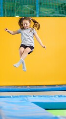 Happy little girl jumping on trampoline in fitness center